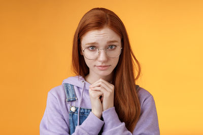 Woman pleading against yellow background