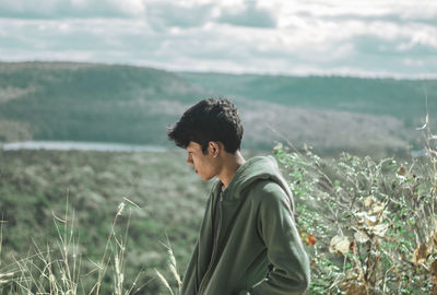 Side view of young man looking away on field