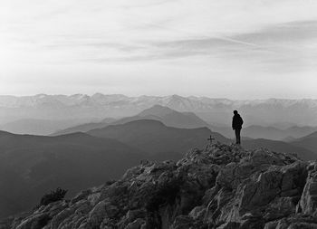 Rear view of man standing on mountain against sky