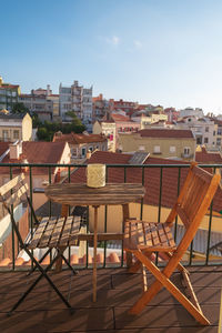 Chairs and table by buildings in city against sky