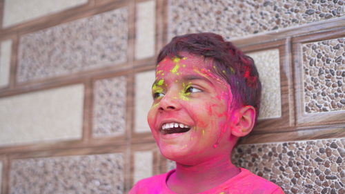 Cute little boy posing with exploding pink and green holi powder around his.