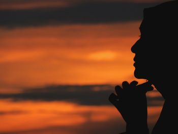 Close-up of silhouette woman against orange sky during sunset