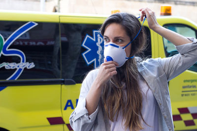 Woman looking away while wearing mask against ambulance