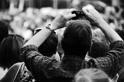 Rear view of man photographing while standing with people