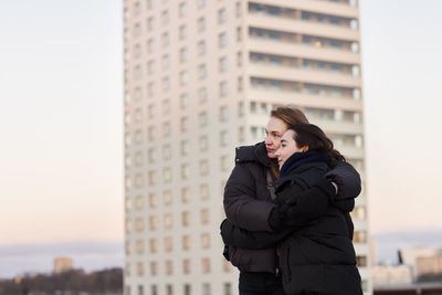 Female couple hugging in modern neighborhood