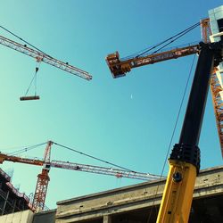 Low angle view of crane against clear blue sky