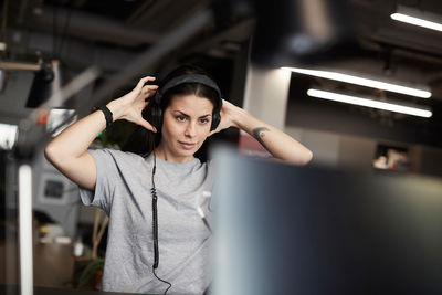 Creative businesswoman wearing headphones while looking at computer monitor in office