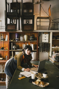 Portrait of female entrepreneur working on laptop in upcycling store