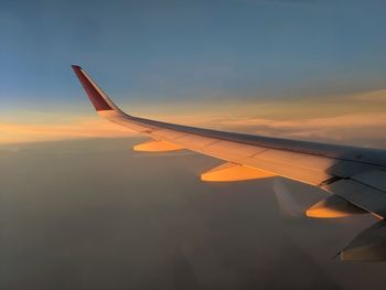 Airplane flying in sky at sunset