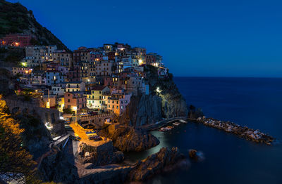 Aerial view of illuminated town by sea against clear sky