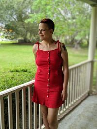 Young woman looking away while standing by railing in porch