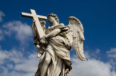 Low angle view of angel sculpture against blue sky