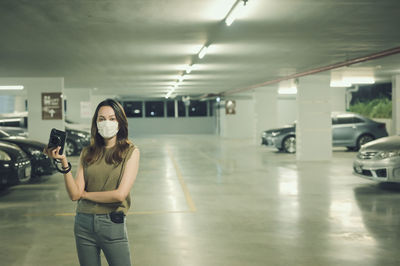Young woman standing in car park building and hand holding camera in smart emotion