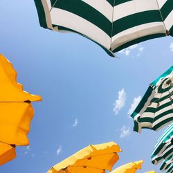 Low angle view of beach umbrellas against blue sky