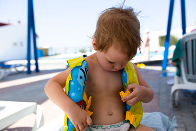 Small child in panama hat plays in the summer on sunny day near swimming pool