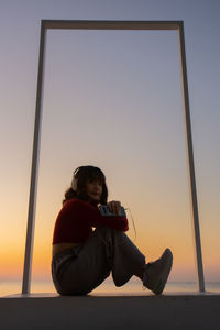 Portrait of woman sitting against sky during sunset