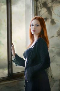 Portrait of young woman standing against wall