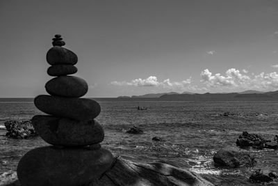 Stack of stones in sea against sky