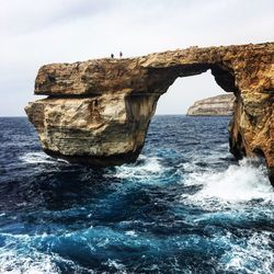 Rock formation in sea against sky