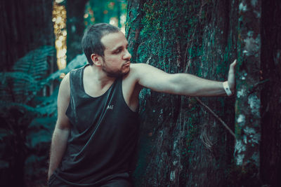 Portrait of young man looking away in forest