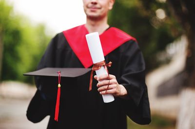 Midsection of male university student holding degree