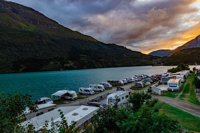 Calming view on camping people by the fjord shore against mountains and dramatic clouded sky