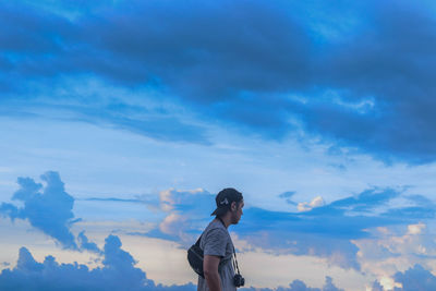 Side view of woman standing against blue sky