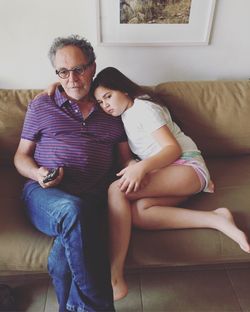 Cute girl with grandfather watching television at home