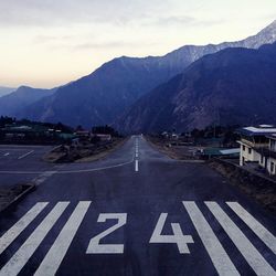 Road by mountains against sky