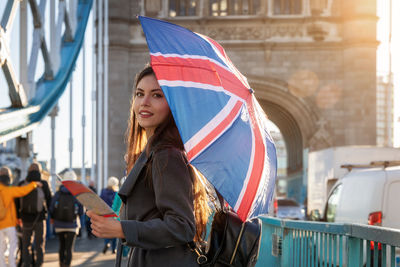 Beautiful woman standing with umbrella on bridge