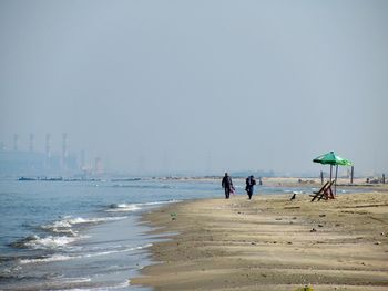 People on beach against clear sky
