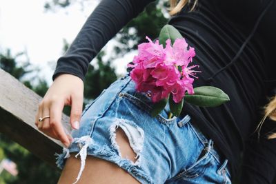 Midsection of woman with flower in pocket standing outdoors