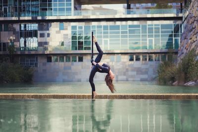 Full length of young woman jumping on water