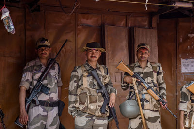 Portrait of army soldiers with guns standing against built structure