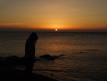 Silhouette of people standing on beach at sunset