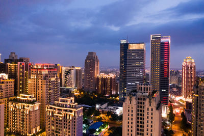 Illuminated buildings in city against sky