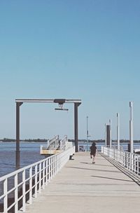 Railing by sea against clear sky