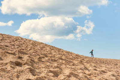 Man on sand dune against sky