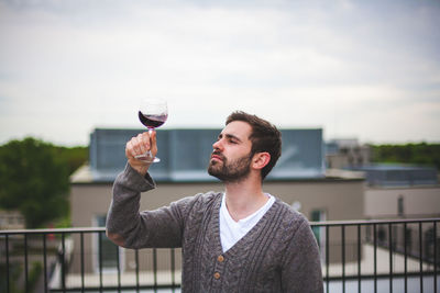 Young man drinking glasses on railing