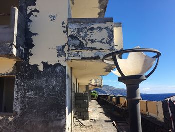 Broken street light by old abandoned house on sunny day