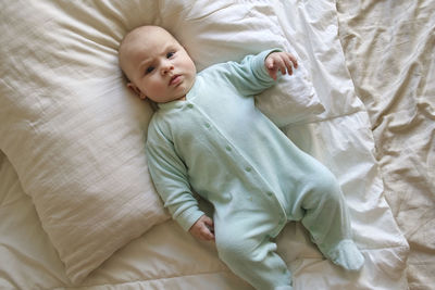 Cute newborn baby lying on the back in a child crib on white. portrait of little energetic child