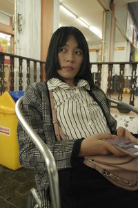 Portrait of young woman sitting in corridor