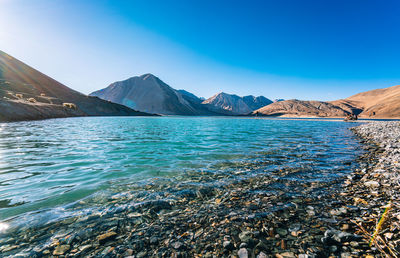 Scenic view of sea and mountains against clear blue sky