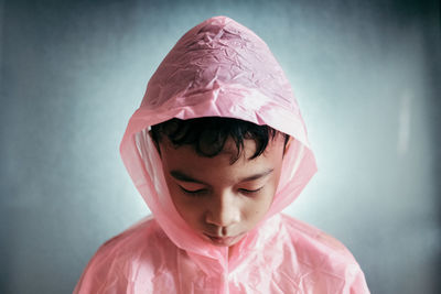 Close-up of boy wearing raincoat against wall