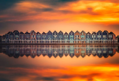 Reflection of houses in river against orange sky