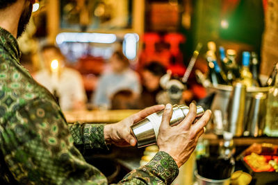 Midsection of bartender holding cocktail shaker