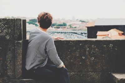 Rear view of woman sitting on wall