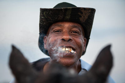 Close-up portrait of man wearing hat against gray background