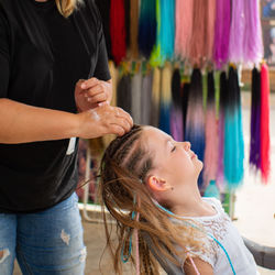 Close up hairstylist braided hair of white caucasian pre teen client in the barber salon.