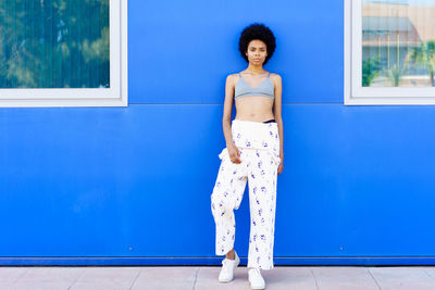 Young woman standing against wall